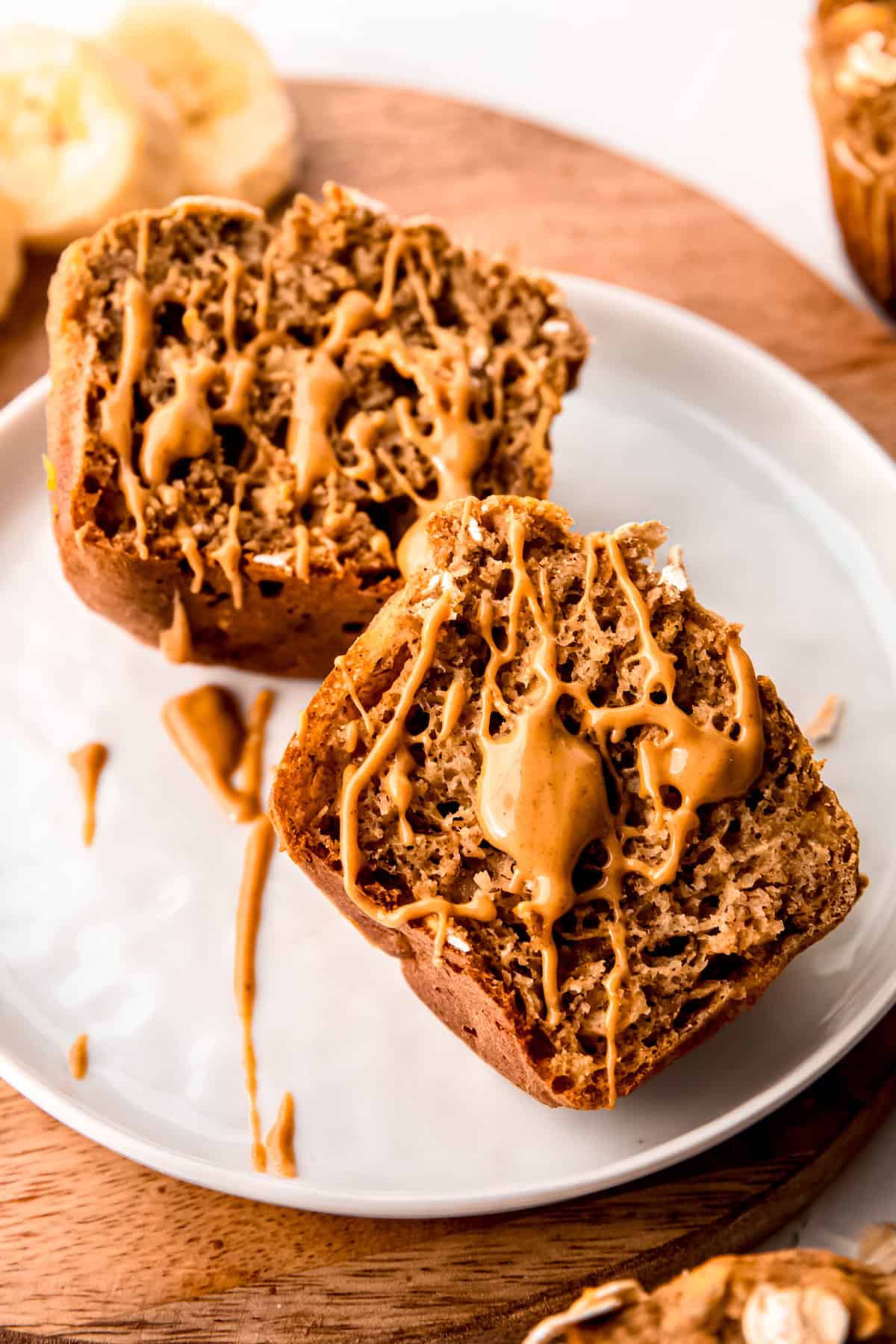 halved whole grain banana nut bread muffin halved and topped with a drizzle of nut butter.