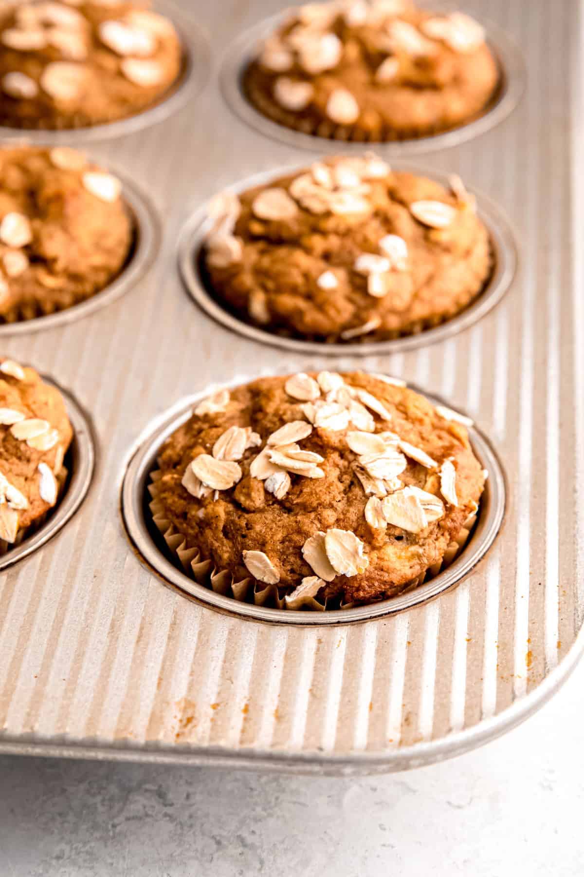 closeup 45 degree angle shot of the bottom right quarter of a muffin tin filled with whole wheat banana muffins.