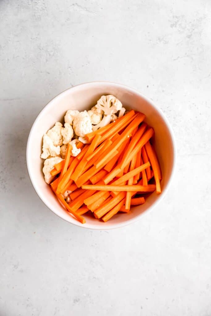 matchstick carrots and bite sized cauliflower florets in a large mixing bowl.