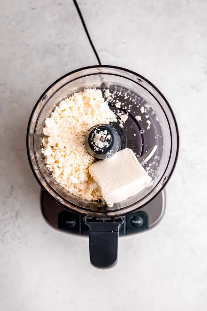 cream cheese and feta added to the base of a food processor.