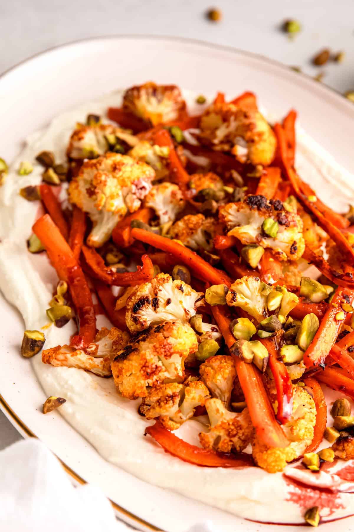 45 degree angle closeup of roasted carrots and cauliflower with whipped feta.